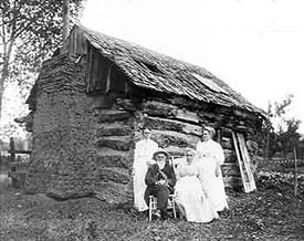 John McBroom cabin on Bear Creek, c.1910. Seated is Isaac McBroom, brother of John; and Isaac's wife Emma. Standing at left is Mrs. McBroom Playter, daughter of Isaac; and at right is Mrs. Etta Neuiheiser, who was in the same wagon train crossing the plains.