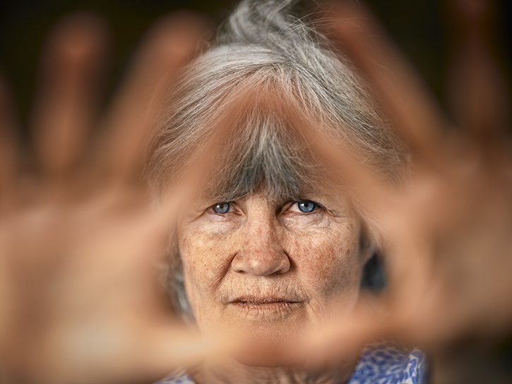 Image of elderly woman holding her hands up around her eyes