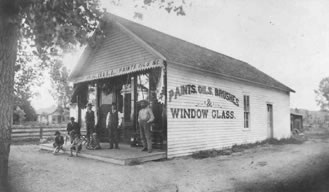 Littleton's first drug store, c.1885-1890, located on the present-day site of the Masonic Hall at 5718 South Rapp St. Standing, left to right: Oscar G. Hill, druggist and owner; Julius D. Hill, John B. Mayers.